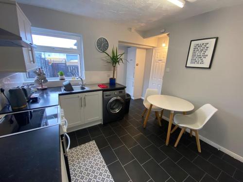a kitchen with a table and a sink and a table at Seaside 2 bed Townhouse, near Cleethorpes station in Cleethorpes