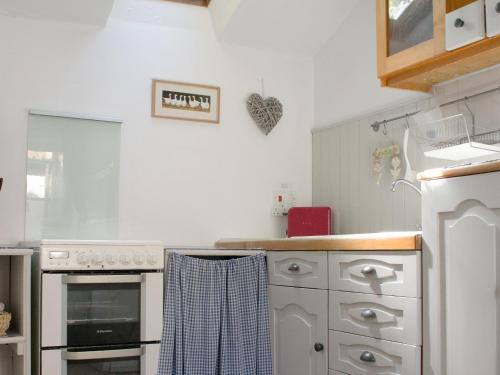 a kitchen with white appliances and a towel on the counter at Hollies Cottage in Draycott