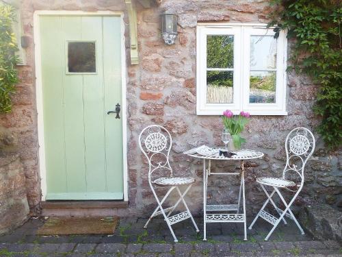 a table and chairs in front of a building with a door at Hollies Cottage in Draycott