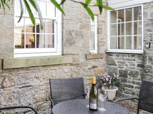 Stocksfield的住宿－The Cottage，一张桌子上摆放着一瓶葡萄酒,还有两把椅子