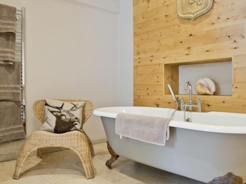 a bathroom with a white bath tub and a chair at The Downs Barn Lodge in Nailsworth