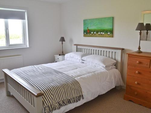 a bedroom with a bed and a painting on the wall at Morys Cottage in Keiss
