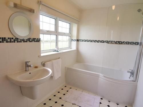 a bathroom with a sink and a tub and a mirror at Riffli - Hw7700 in Abersoch
