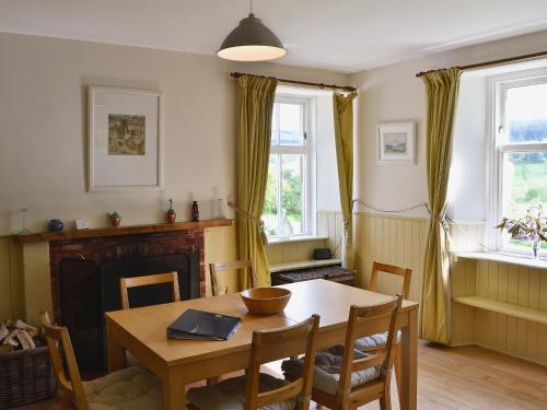 a dining room with a table and chairs and a fireplace at Straitinnan in Haugh of Glass