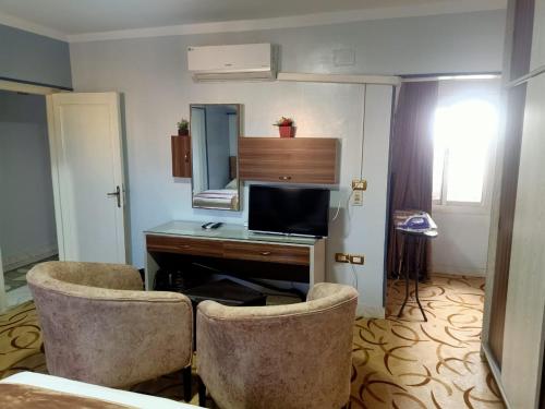 a room with two chairs and a desk with a television at فاكانزا شقة فندقية مفروشة- vacanze in Fayoum Center