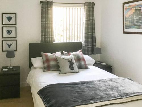 1 dormitorio con cama con almohadas y ventana en Beach Cottage, en Gairloch