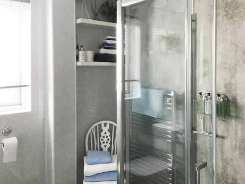 a shower with a glass door and a chair in a bathroom at Beach Cottage in Gairloch