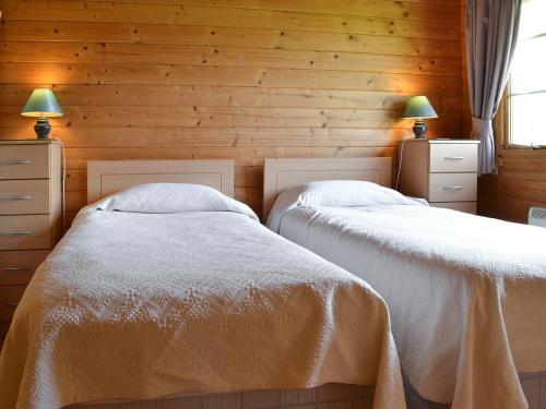 two beds in a bedroom with wooden walls at The Cabin in Wendling