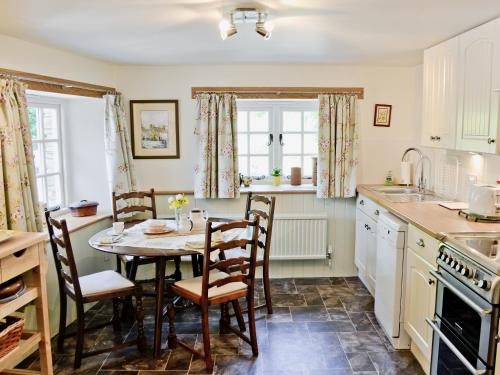 a kitchen with a table and chairs in a room at Peartree Cottage in Northlew