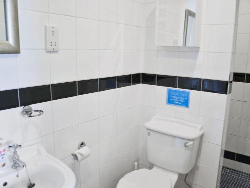 a white bathroom with a toilet and a sink at Quince Cottage - 27443 in Sedlescombe