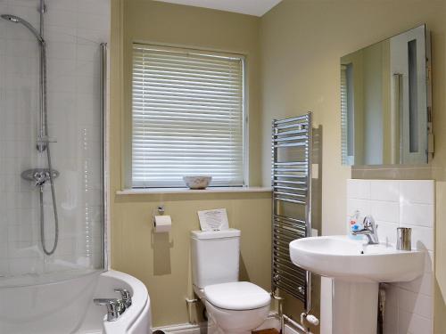 a bathroom with a toilet and a sink and a shower at Chesnut Cottage - 27524 in Sewerby