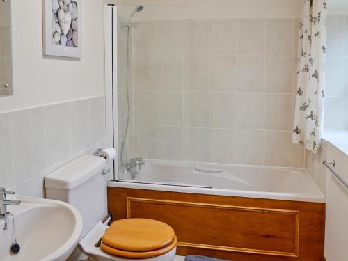 a bathroom with a toilet and a tub and a sink at The Old Piggeries in Loders