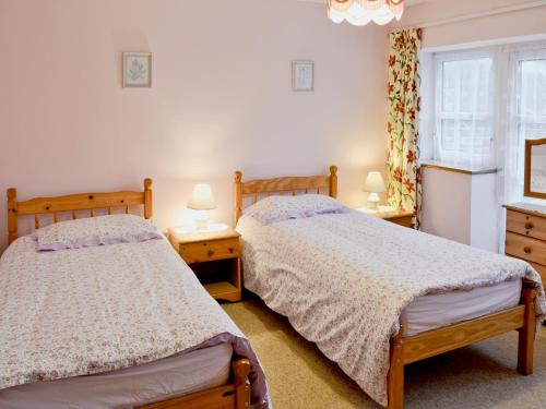 2 camas num quarto com 2 candeeiros e uma janela em The Old Piggeries em Loders