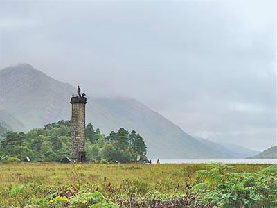 a lighthouse in a field next to a body of water at Blythswood in Glenfinnan