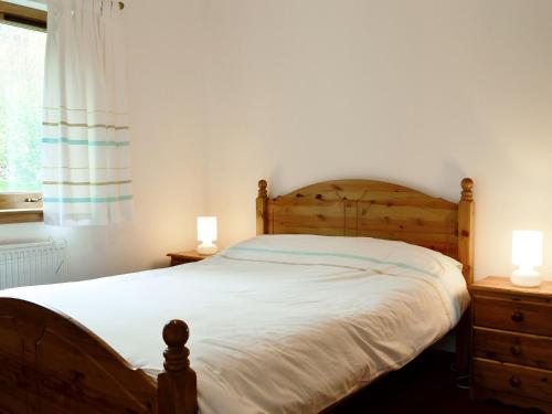 a bedroom with a wooden bed with two lamps at Blythswood in Glenfinnan