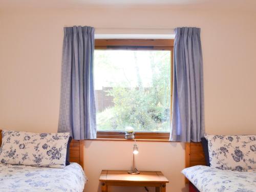 a bedroom with a window with blue curtains at Squirrel Cottage in Kilmuir