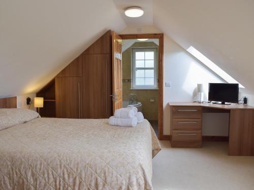 1 dormitorio con 1 cama y escritorio con TV en Ty-canol, en Ferryside