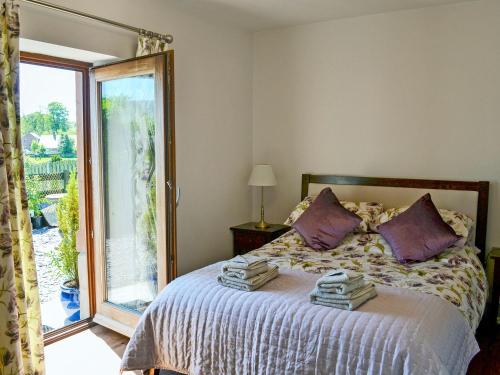 1 dormitorio con 1 cama y puerta corredera de cristal en Blackhill Cottage, en Farlam