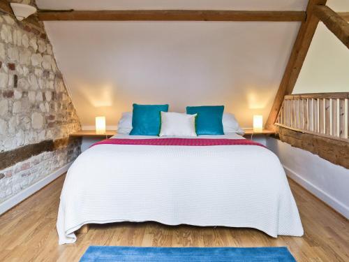 una camera da letto con un letto bianco con cuscini blu di The Granary a Oxborough