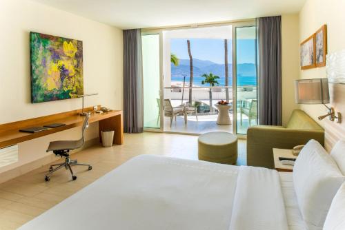 ein Hotelzimmer mit einem Bett, einem Schreibtisch und einem Stuhl in der Unterkunft Krystal Grand Puerto Vallarta - All Inclusive in Puerto Vallarta