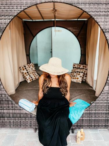 a woman in a black dress and hat sitting in front of a mirror at Bayside Inn Key Largo in Key Largo