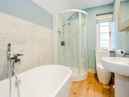 a bathroom with a shower and a tub and a sink at Rectory Cottage in Blankney