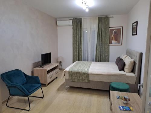 - une chambre avec un lit, une télévision et une chaise dans l'établissement Apartman City kvart, à Podgorica