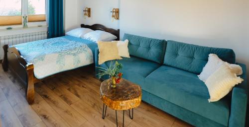 a living room with a blue couch and a table at Apartament Zielony Ruczaj w Cisnej in Cisna