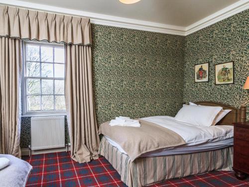 um quarto com uma cama com papel de parede verde em Lochenkit Farmhouse em Corsock
