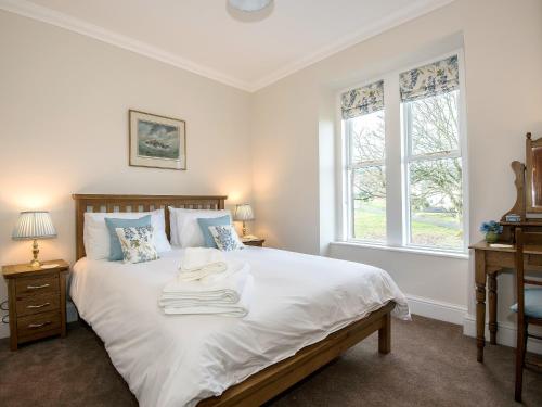 a bedroom with a bed with white sheets and two windows at The Laburnums in Askham
