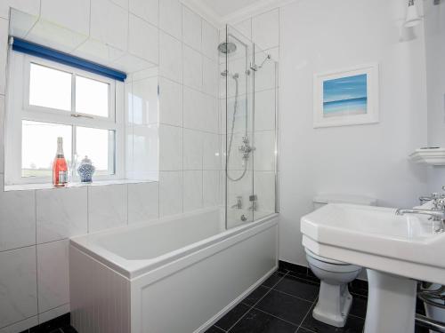 a white bathroom with a tub and a sink at The Laburnums in Askham