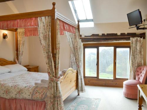 a bedroom with a canopy bed and a window at The Granary in Colyford