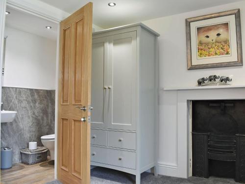 a bathroom with a white cabinet and a fireplace at Peartree Cottage Granary in East Witton