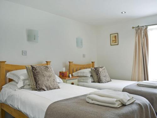 a bedroom with three beds with white sheets at Peartree Cottage Granary in East Witton