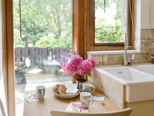 a kitchen with a sink and a table with flowers at The Figgery in Wrangaton