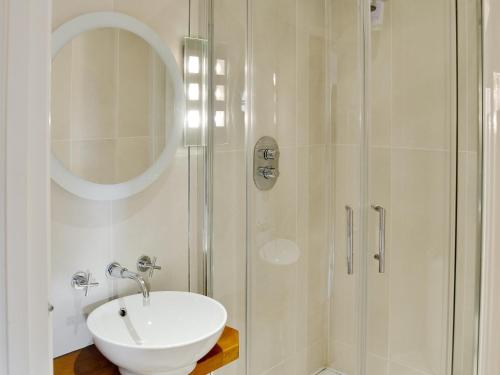 a white bathroom with a sink and a shower at Carnethic House - One Acre View in Fowey