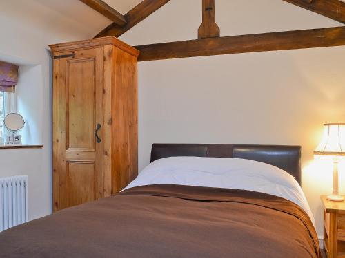 AshoverにあるMulberry Cottageのベッドルーム1室(ベッド1台付)、木製キャビネットが備わります。
