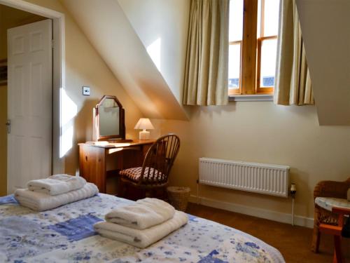 um quarto com uma cama, uma secretária e uma janela em Kirsty Cottage em Moffat