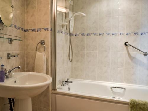 a bathroom with a tub and a sink and a shower at Kirsty Cottage in Moffat