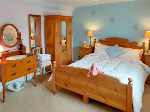 1 dormitorio con 1 cama con tocador y espejo en Cow Cottage, en Churchill
