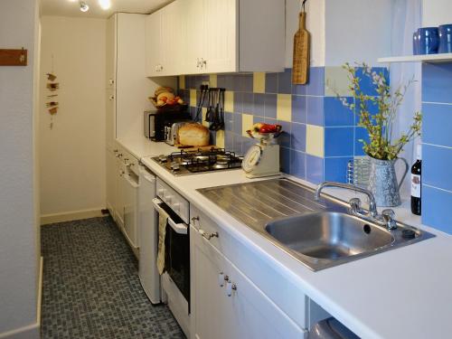 a small kitchen with a sink and a stove at Beachside Cottage in Shaldon