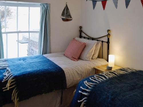 a bedroom with two beds and a window with a candle at Beachside Cottage in Shaldon