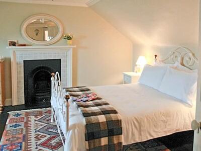 a bedroom with a bed with a fireplace and a mirror at The Cottage in Garlieston