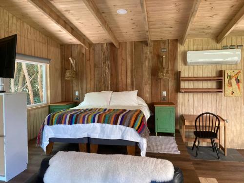 a bedroom with a bed in a wooden room at Cabañas Almalik in Ralún