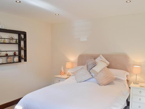 a bedroom with a white bed with two night stands at Paper Mill Cottage in Sutton