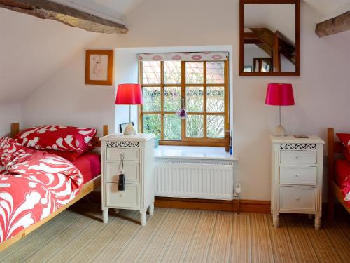 a bedroom with a bed and two night stands and a window at Cruck Cottage in Sinnington