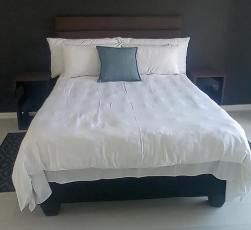 uma grande cama branca com almofadas azuis em Rachimy em Walvis Bay