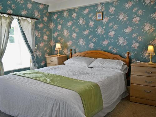 een slaapkamer met een groot bed met bloemenbehang bij Nyffryn Bella in Llandudwen
