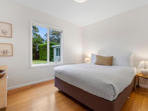 科爾斯灣的住宿－福瑞齊奈飛世度假屋，白色的卧室设有一张大床和一个窗户