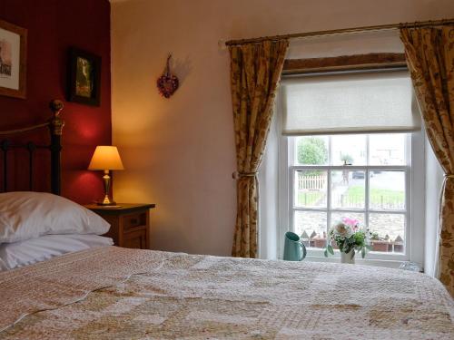 a bedroom with a bed and a window at Tanners Cottage in Cockermouth